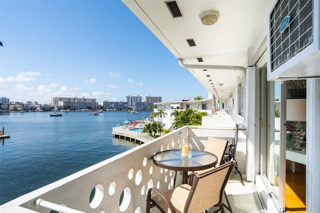 balcony featuring visible vents, a view of city, and a water view