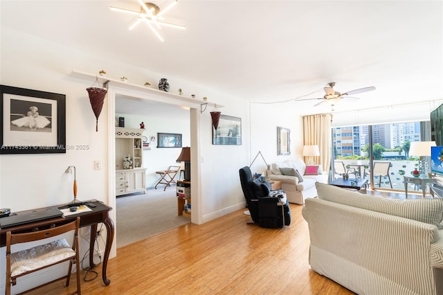 living room with light wood-type flooring, ceiling fan, and expansive windows