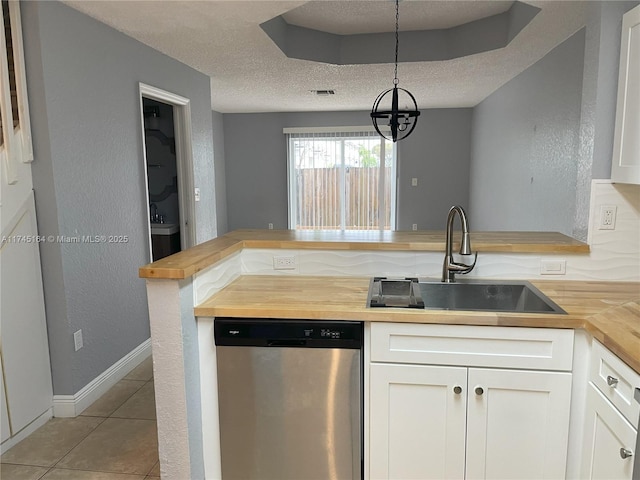 kitchen featuring white cabinets, butcher block counters, hanging light fixtures, stainless steel dishwasher, and a sink