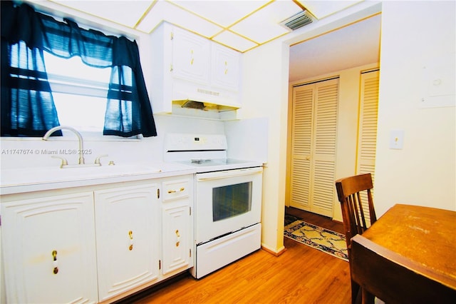 kitchen featuring electric stove, light countertops, visible vents, and white cabinetry