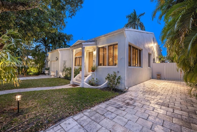 view of front of house with fence, a front lawn, and stucco siding