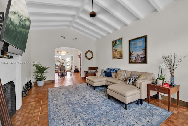 living room with arched walkways, beamed ceiling, visible vents, and baseboards