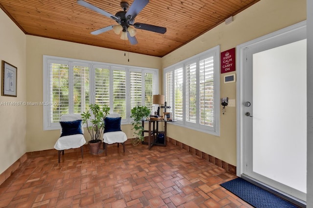 unfurnished room with wooden ceiling, ceiling fan, baseboards, and brick floor