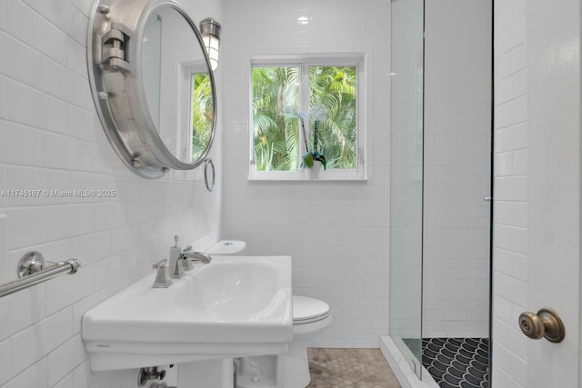 full bathroom featuring a sink, walk in shower, toilet, and tile walls