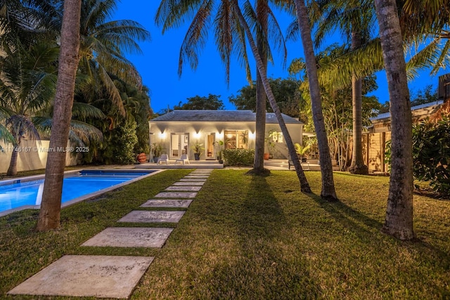 pool with an outbuilding, a patio, a lawn, and an exterior structure