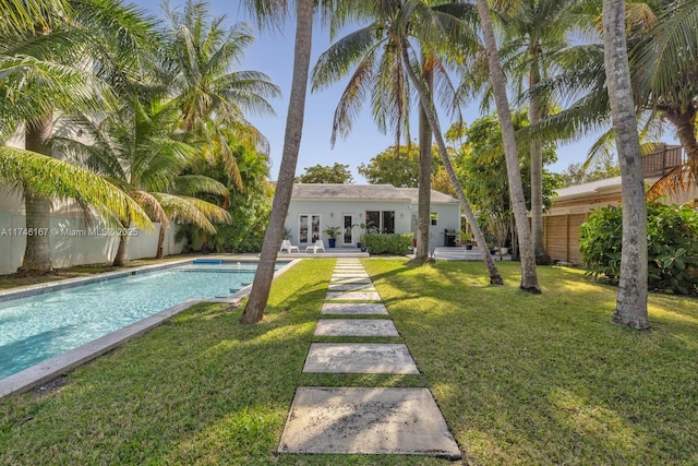 exterior space with a fenced in pool, french doors, a lawn, and fence