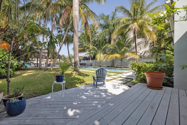 wooden terrace featuring a lawn, fence, and a fenced in pool