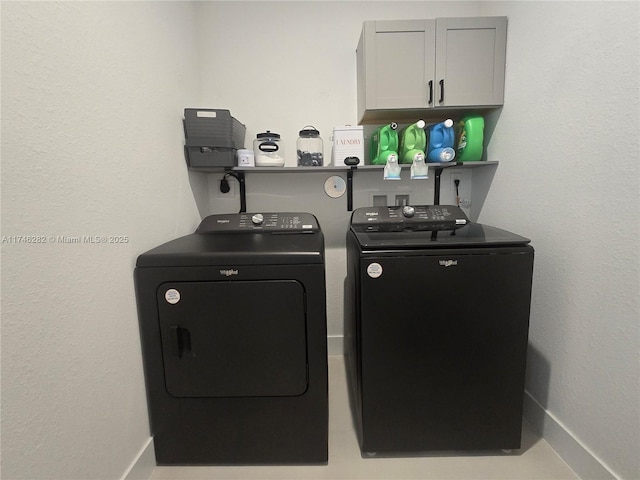 clothes washing area with cabinets and washer and clothes dryer
