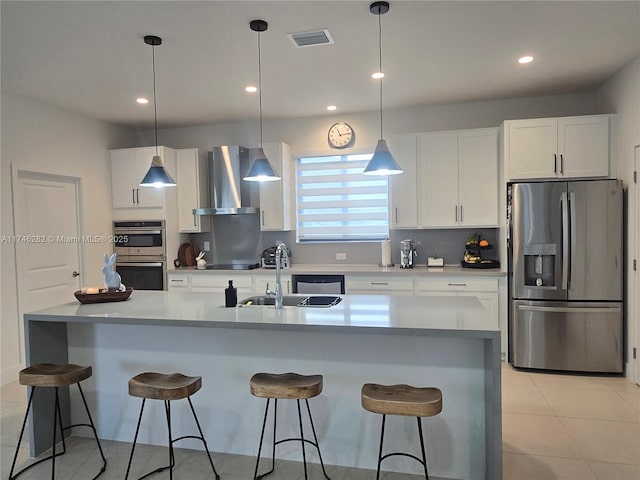kitchen featuring white cabinets, pendant lighting, stainless steel appliances, and wall chimney exhaust hood