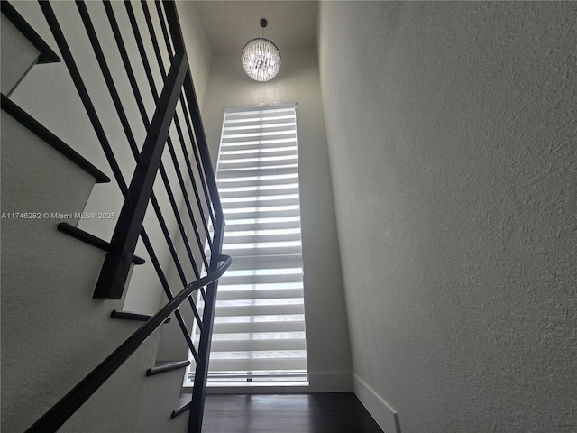 stairway featuring a notable chandelier and wood-type flooring