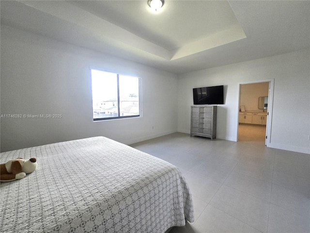 tiled bedroom featuring a raised ceiling and connected bathroom