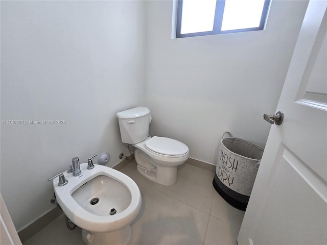 bathroom with a bidet, toilet, and tile patterned floors