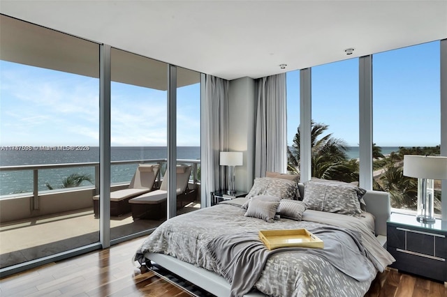 bedroom with a wall of windows, a water view, wood-type flooring, and multiple windows