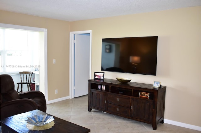 living area featuring light tile patterned flooring, a textured ceiling, and baseboards