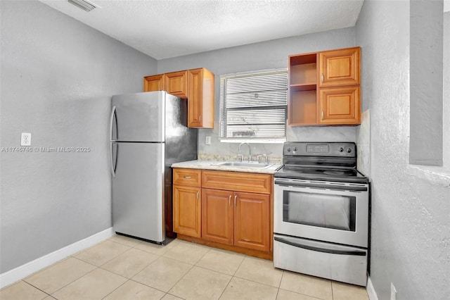 kitchen with sink, appliances with stainless steel finishes, a textured ceiling, and light tile patterned flooring