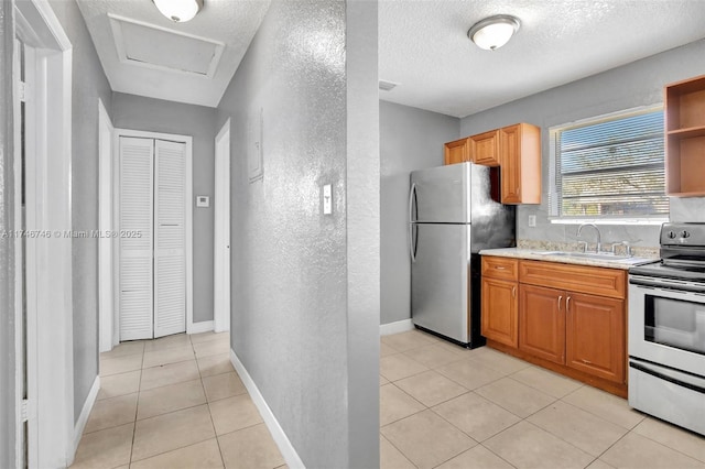 kitchen with appliances with stainless steel finishes, light tile patterned floors, sink, and a textured ceiling