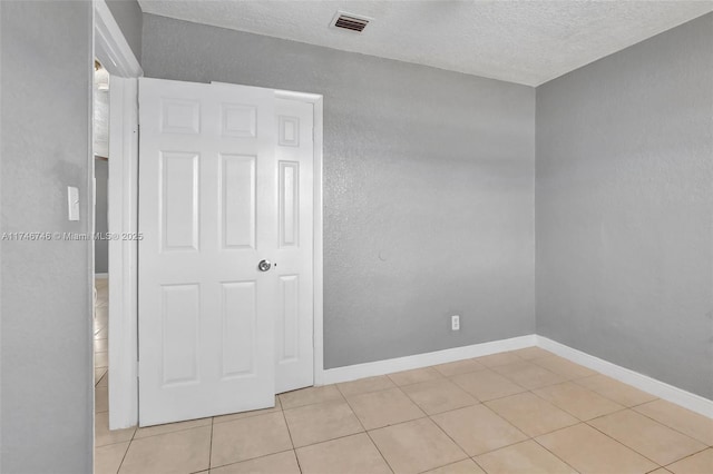 tiled empty room featuring a textured ceiling