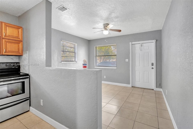 kitchen featuring light tile patterned flooring, stainless steel range with electric cooktop, ceiling fan, and a textured ceiling