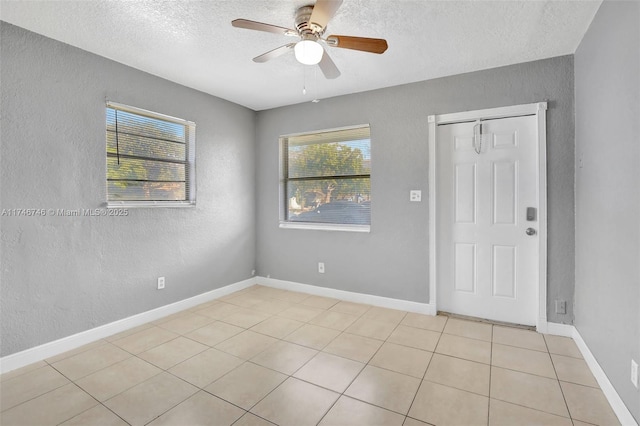 tiled spare room featuring ceiling fan, plenty of natural light, and a textured ceiling