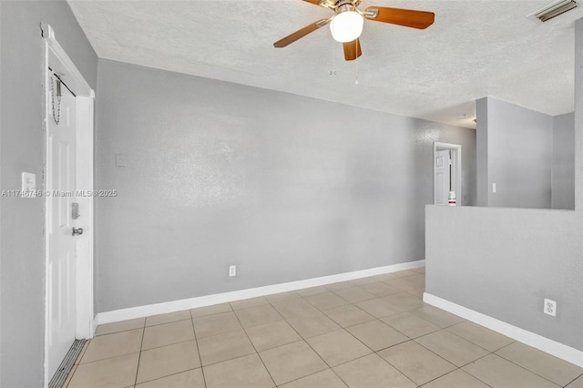 empty room featuring ceiling fan, light tile patterned floors, and a textured ceiling