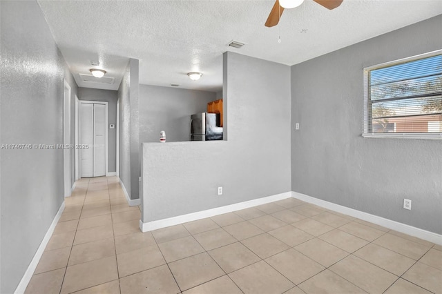 tiled spare room with ceiling fan and a textured ceiling