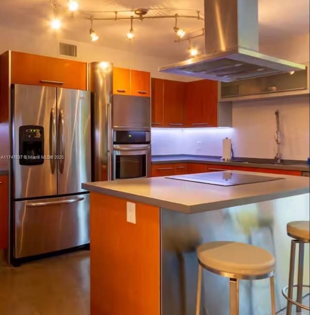 kitchen featuring appliances with stainless steel finishes, concrete floors, island exhaust hood, and a breakfast bar area