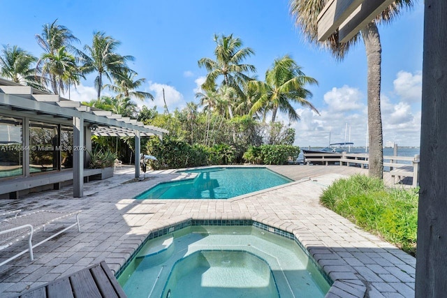 pool with an in ground hot tub, a patio, a water view, and a pergola