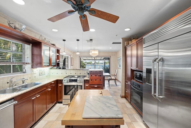 kitchen featuring decorative light fixtures, stainless steel appliances, a sink, decorative backsplash, and glass insert cabinets