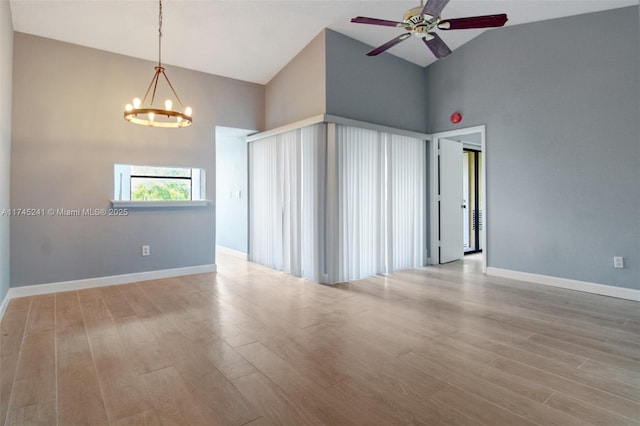 unfurnished room featuring high vaulted ceiling, light hardwood / wood-style floors, and ceiling fan with notable chandelier