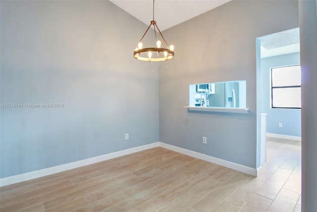 unfurnished room featuring an inviting chandelier, light hardwood / wood-style flooring, and vaulted ceiling