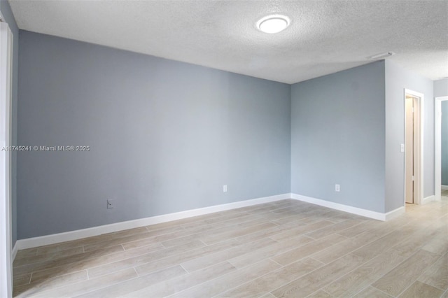 spare room with a textured ceiling and light hardwood / wood-style flooring