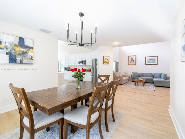 dining room featuring light wood-type flooring and a notable chandelier