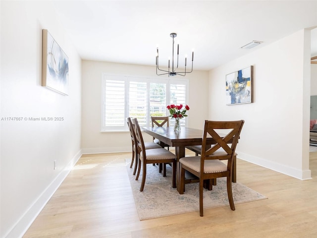 dining space with light wood-type flooring and a chandelier