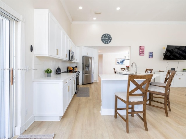 kitchen with appliances with stainless steel finishes, light wood-type flooring, crown molding, sink, and white cabinetry