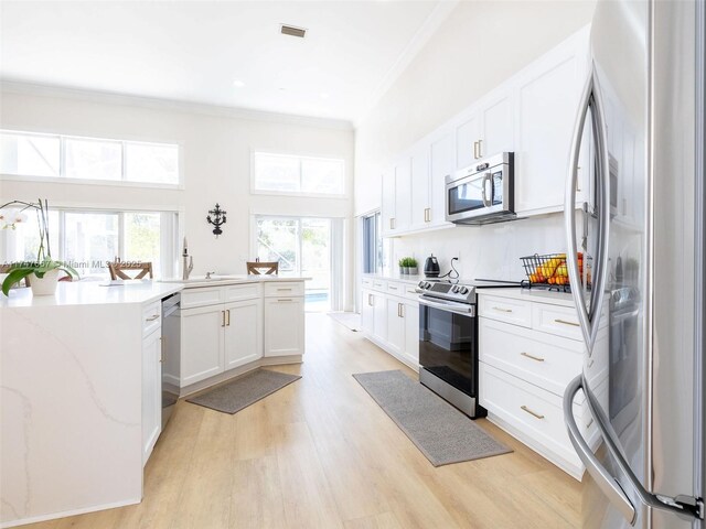 kitchen featuring white cabinetry, light hardwood / wood-style flooring, sink, appliances with stainless steel finishes, and crown molding