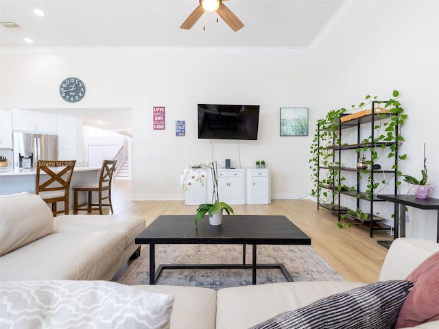 living room featuring ceiling fan, light hardwood / wood-style floors, and crown molding