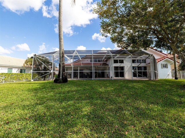 rear view of property with a yard and glass enclosure