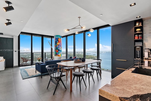 tiled dining area featuring a wall of windows, a water view, and a wealth of natural light