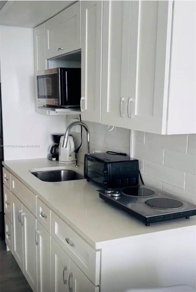 kitchen with sink, tasteful backsplash, and white cabinets