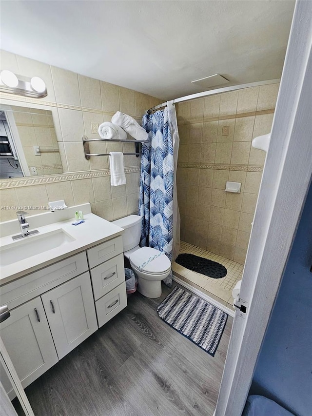 bathroom featuring tile walls, hardwood / wood-style floors, vanity, and walk in shower