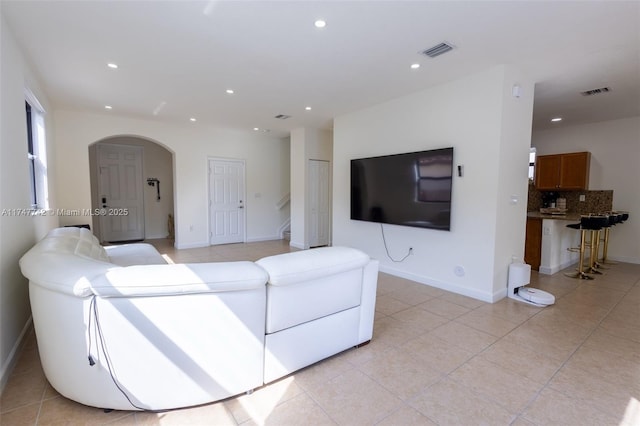 living area with arched walkways, baseboards, visible vents, and recessed lighting