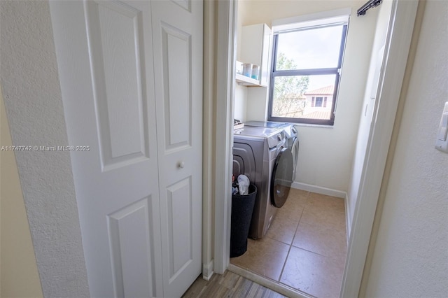 laundry room with washing machine and dryer, laundry area, light tile patterned flooring, and baseboards