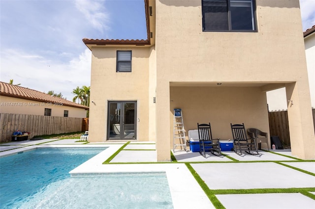 back of house featuring fence, french doors, a fenced in pool, stucco siding, and a patio area