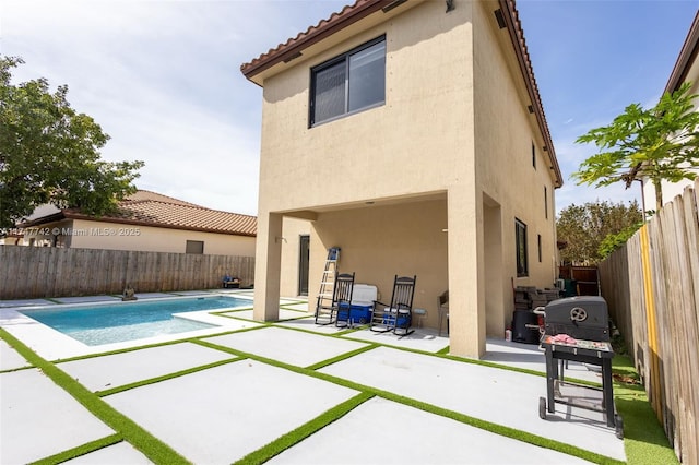 rear view of property with a tiled roof, a patio area, a fenced backyard, and stucco siding