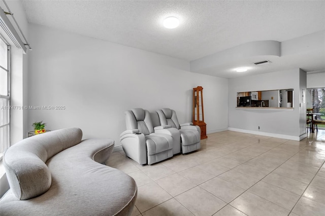 living area with light tile patterned floors, a textured ceiling, visible vents, and a wealth of natural light