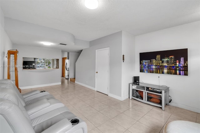 living area featuring light tile patterned floors, baseboards, visible vents, and a textured ceiling