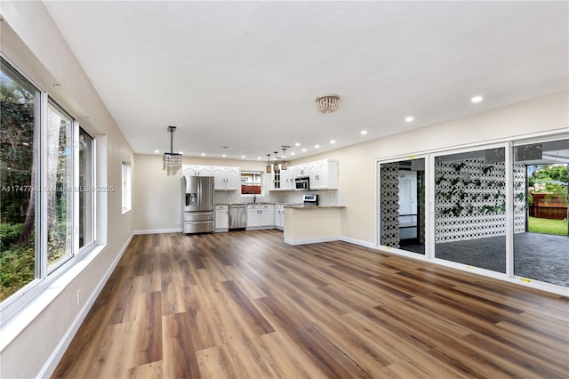 unfurnished living room with a notable chandelier and dark hardwood / wood-style floors