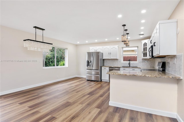 kitchen with appliances with stainless steel finishes, sink, hanging light fixtures, and white cabinets