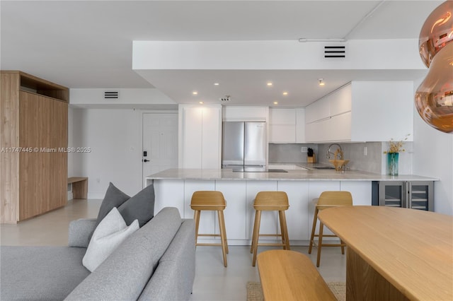 kitchen featuring finished concrete floors, a peninsula, freestanding refrigerator, and a sink