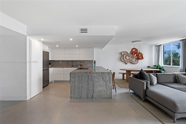 living area with baseboards, recessed lighting, visible vents, and finished concrete floors